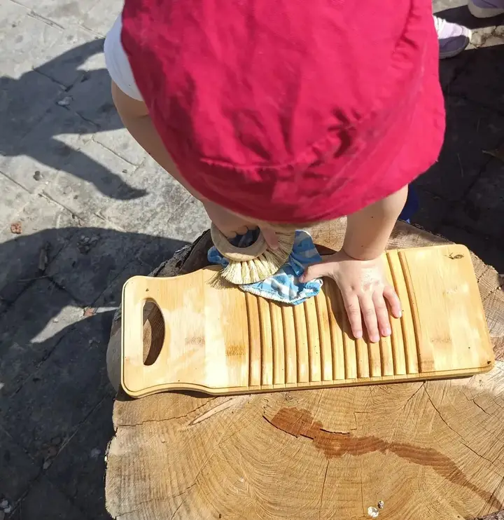 Unas manitas juegan con una tabla de lavar de madera